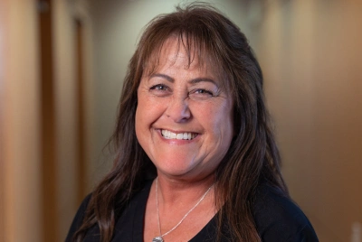 Woman smiling at camera in professional indoor setting for orthodontics practice