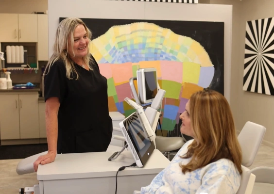 Orthodontist discusses dental model with patient in modern office setting with colorful artwork.